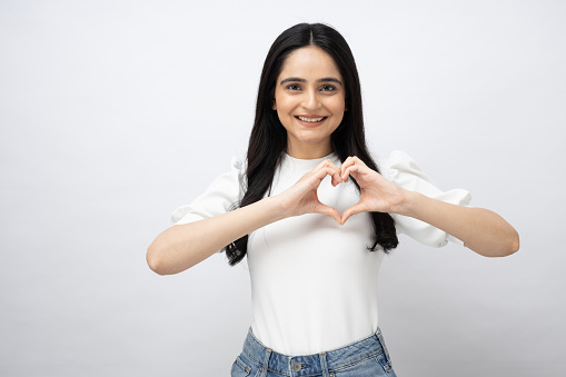 Cute beautiful girl in love making heart with fingers and smiling