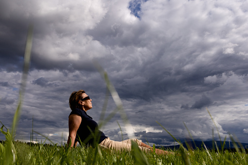 A tourist is resting on a field under dark low clouds