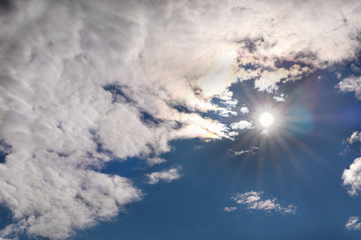 Blue sky with a white fluffy cloud and the sun. Copy space