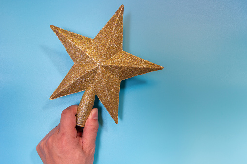 Gold tree topper and star isolated on blue background