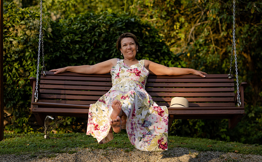 A woman with a smile sways on a park bench
