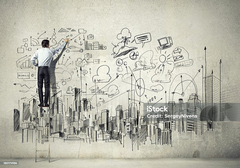 Businessman drawing business elements on the wall Back view of businessman drawing sketch on wall Business Stock Photo