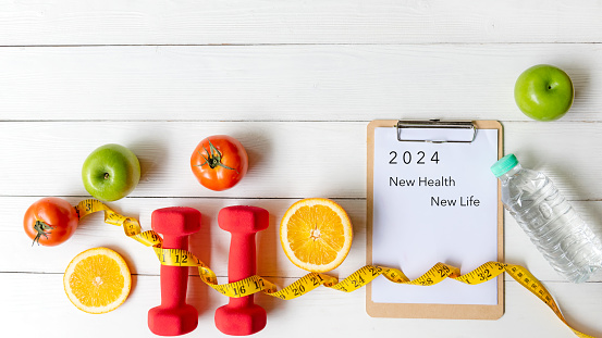 2024 NEW HEALTH AND NEW LIFE.  New year for New Changes Healthy.  Fresh vegetable fruits and healthy food for sport equipment for women diet slimming weight loss on white wood.  Healthy and Holiday Concept