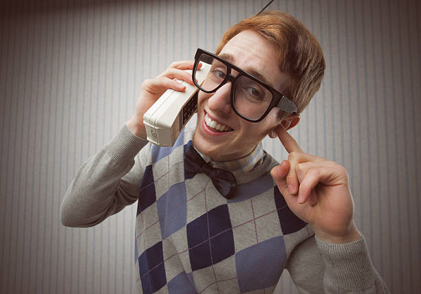 nerd estudiante con un viejo teléfono móvil - bizarre nerd humor telephone fotografías e imágenes de stock