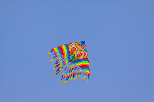 Colorful kite is flying in a blue sky.