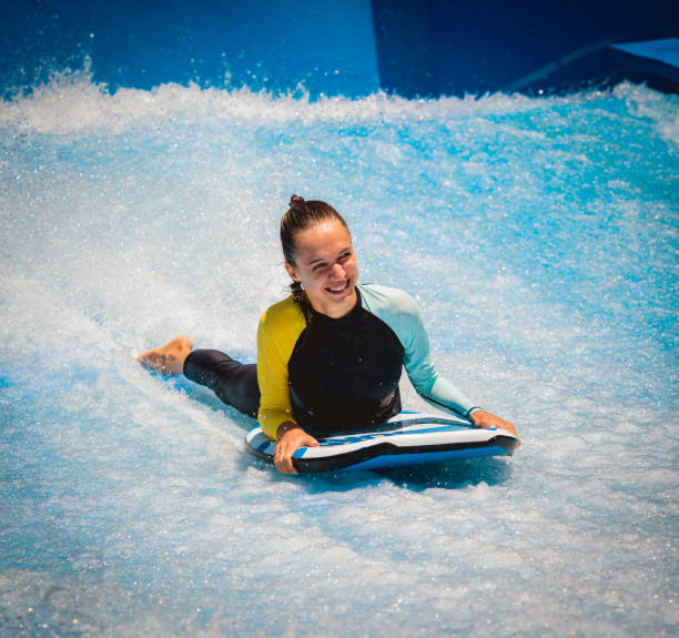 istock Beautiful young woman surfing on a wave simulator at a water amusement park 1801815882