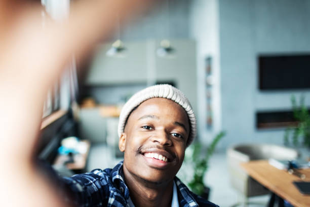 istock One young adult black man making selfie using mobile at home 1801823174