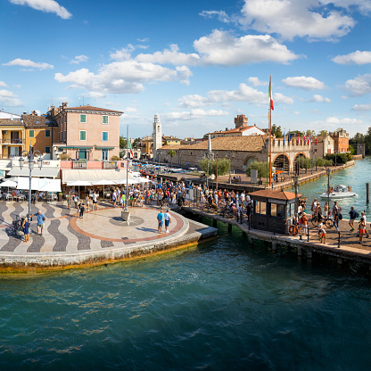 Holidays in Italy - tourists waiting for the ferry at the pier in the tourist resort of Lazise on Lake Garda