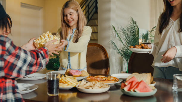 istock Group of young Asian people preparing and having fun sitting at dining table at home. Multicultural friends having fun together college house party. 1801866963