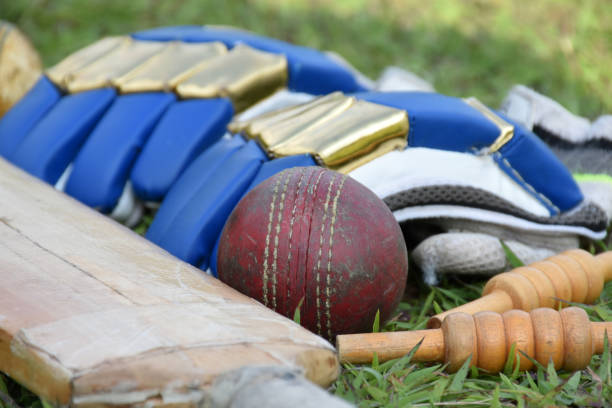 Old leather cricket balls and cricket sportwears on the green grass lawn, concept for practicing cricket sports.