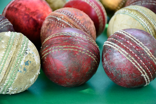 Old training cricket sport equipments on dark floor, leather ball, wickets, helmet and wooden bat, soft and selective focus, traditional cricket sport lovers around the world concept.