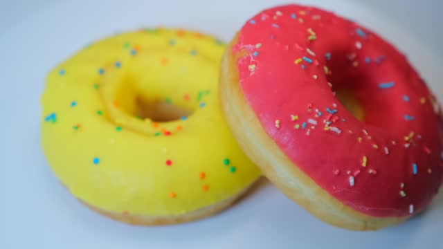 Yummy donuts background, with yellow and pink glaze and colorful sprinkles, strawberry and banana flavors