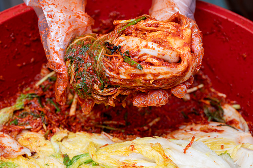 The process of making a traditional Korean dish, kimchi. Close-up of a woman's hand making cabbage kimchi by adding various seasonings to salted cabbage