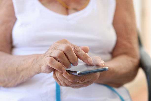istock Elderly woman hand with smartphone texting at home 1801934285
