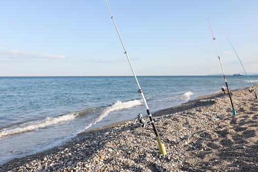 Fishing rods on Mediterranean Sea on beach. Seaside landscape and fishing concept