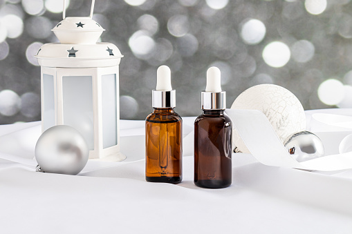Two cosmetic bottles with a pipette with a natural self-care product on a festive New Year background. Product presentation. Blank bottle mockup