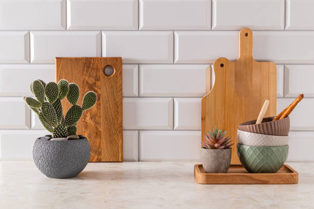 istock Set of ceramic bowls and cutting boards on stone light countertop in modern kitchen with potted opuntia, cactus . Front view. minimalism. 1801960544