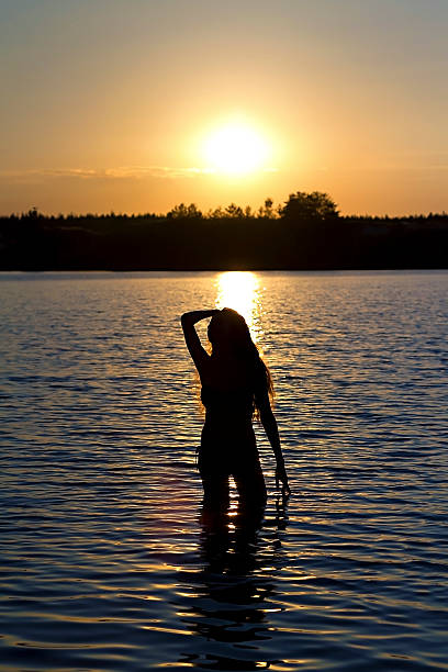 istock girl standing in the lake at sunset 180198178