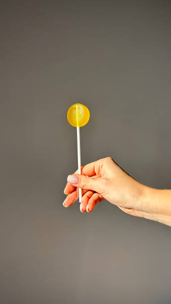 istock woman hand with yellow lollipop isolated 1801996021