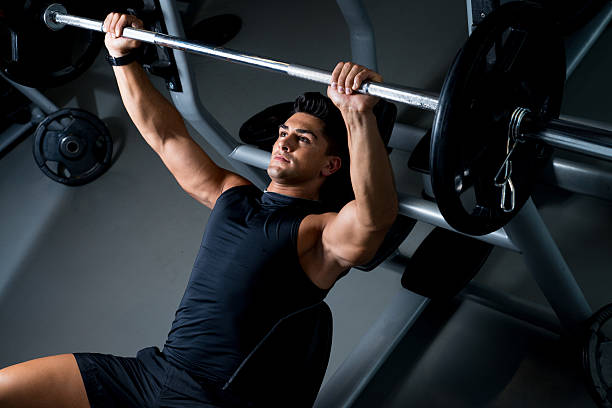 A man lifting weights on a bench press stock photo