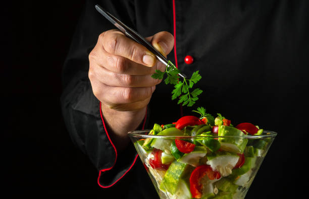 The chef prepares a salad with fresh vegetables in the restaurant kitchen. Vegetable dish in a breakfast bowl. Vegetarian healthy food concept