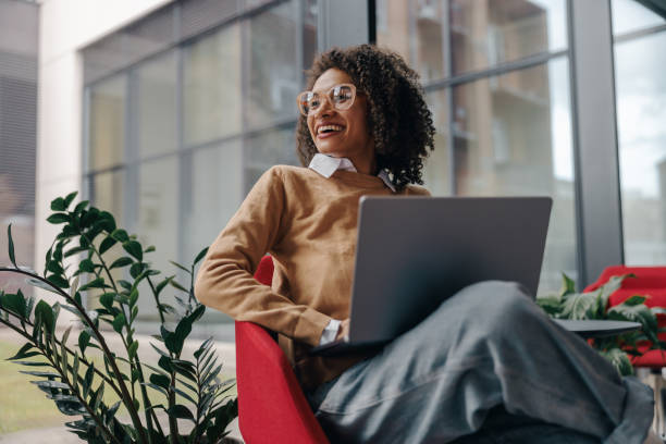 istock Smiling business woman using laptop while sitting on modern office background 1802011661