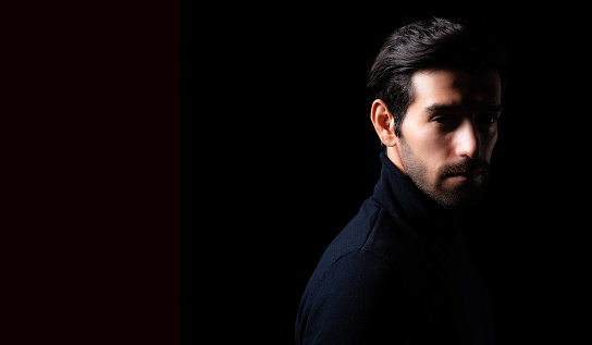 Handsome young business man portrait Attractive bearded guy get confident He look at camera Smart man stand in the dark room Confidence Cool man looking at camera copy space Business Fashion concept
