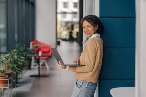 istock Smiling female manager using laptop while standing on office background and looks camera 1802014531