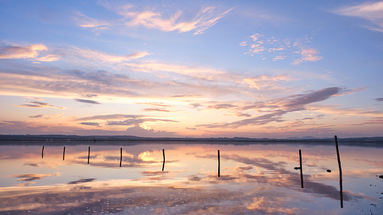 Sunset on the salt lagoon with reflections of clouds and silhouettes of reflections