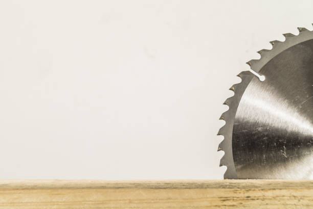 Circular saw blade for wood work on wood board with white background.