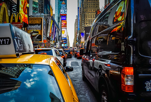 Manhattan, New York, USA - August 16, 2014.\nBusy traffic pulsing through the Times Square in New York City. Road full of cars, yellow cabs and sounds. Crossing the street. Every day life.