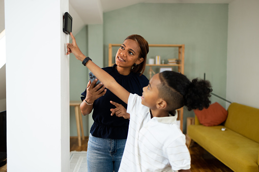 Latin woman and her son setting up smart home system at their apartment.
