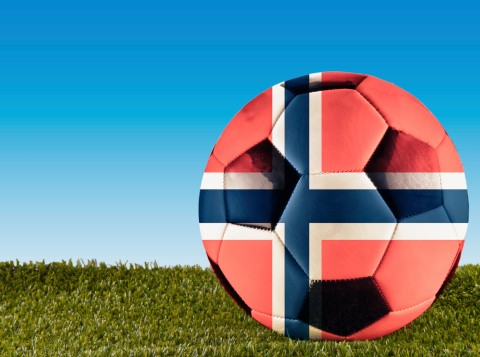 A football over grass decorated with Norway flag