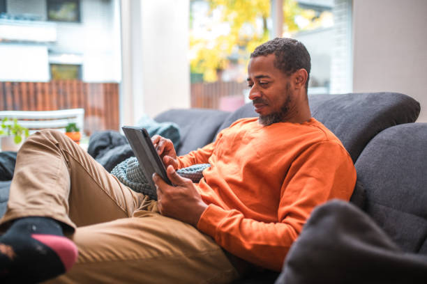 istock Mid Adult Black Male on Sofa with Digital Tablet 1802051496