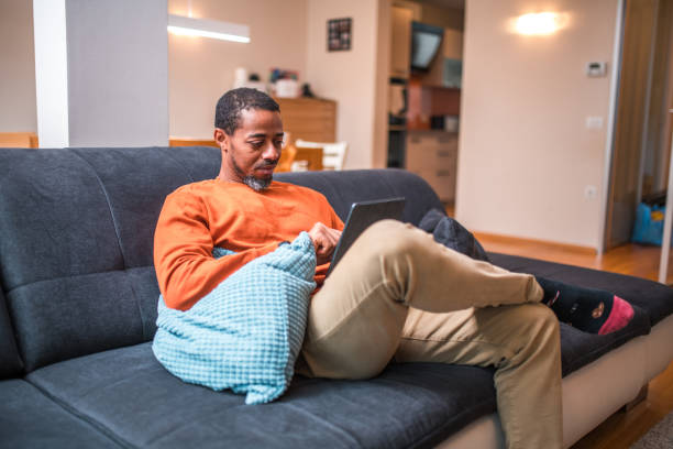 istock Mid Adult Black Male on Sofa with Digital Tablet 1802051499