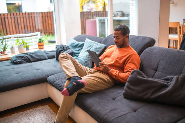 istock Mid Adult Black Male on Sofa with Digital Tablet 1802052007
