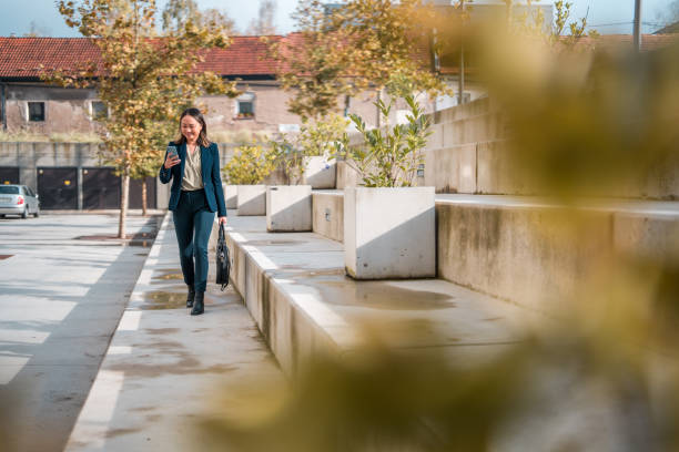 istock Asian Businesswoman Walking and Using Smartphone 1802053733