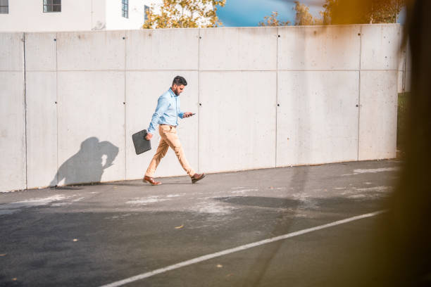 istock Indian Male Walking Outdoors Using Smartphone 1802054293