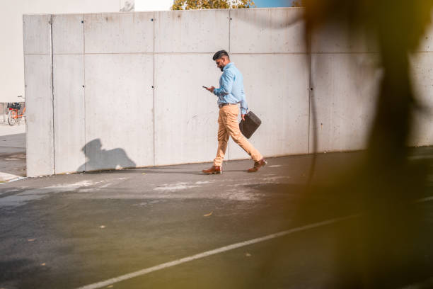 istock Indian Male Walking Outdoors Using Smartphone 1802054299