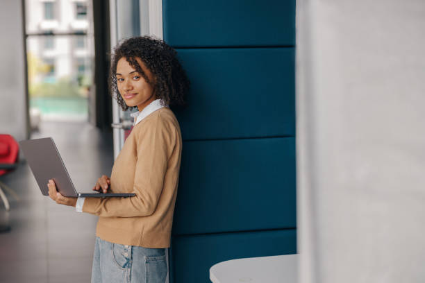istock Smiling female manager using laptop while standing on office background and looks camera 1802056991
