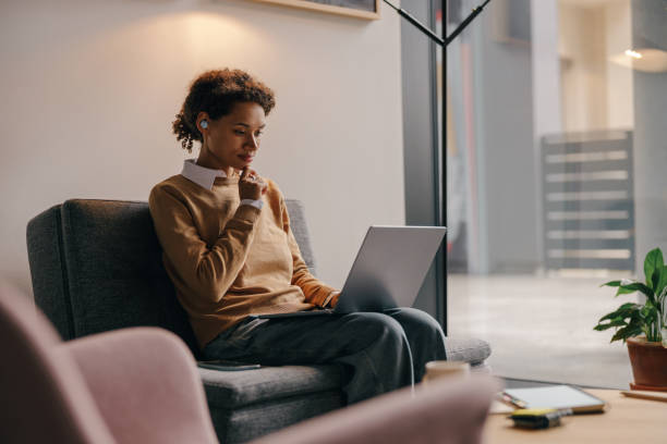 istock Focused female manager using laptop while sitting on cozy office background 1802059137