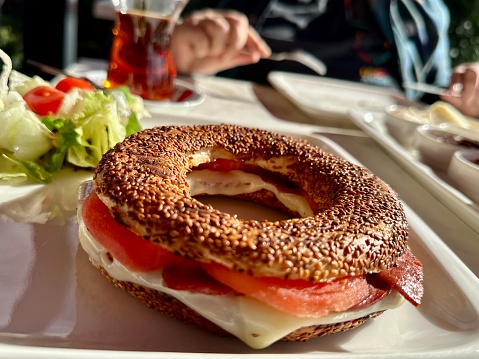 Fresh healthy bagel sandwich with salmon, ricotta and soft egg on vintage chopping board on stone kitchen table background