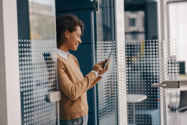 istock Stylish female freelancer is using mobile phone standing in coworking during break time 1802076328