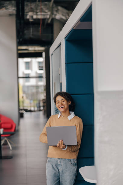 istock Smiling female entrepreneur using laptop while standing on office background and looks camera 1802077380