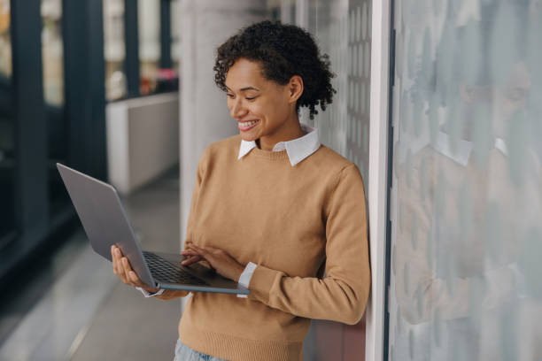 istock Smiling female entrepreneur using laptop while standing on modern office background 1802077901