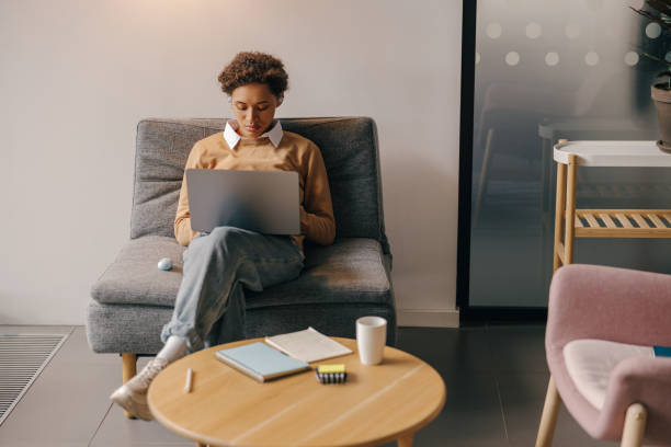 istock Focused business woman using laptop while sitting on modern office background 1802079463