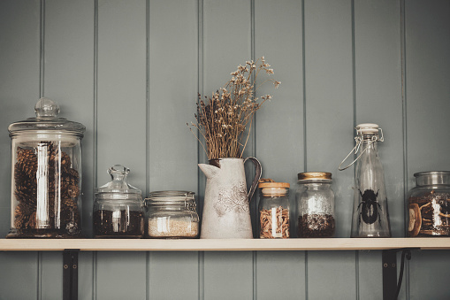 Witches kitchen. Shelf with vintage various glass jars and dry herbs, close-up, cinematic style. Atmospheric, authentic, magic mood, rustic, pagan, old-fashioned stuff concept