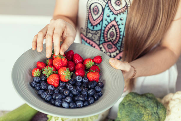 istock Female hands with a white plate with fresh strawberries and blueberries on the kitchen, close-up, selective focus. 1802103848