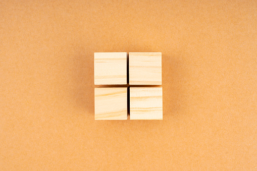 Pyramid of four blank wooden cubes, on brown background.