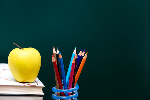 Back to school supplies on blackboard background.